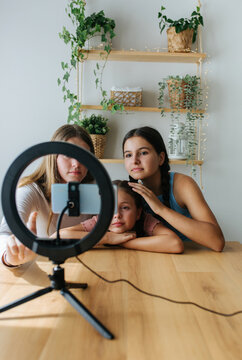 Cheerful sisters recording video at home