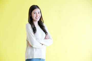 Happy asian woman arm cross, smiling and looking at camera while standing over isolated yellow background, Portrait of asia female