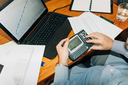 Top view of male hands using calculator while working with graph