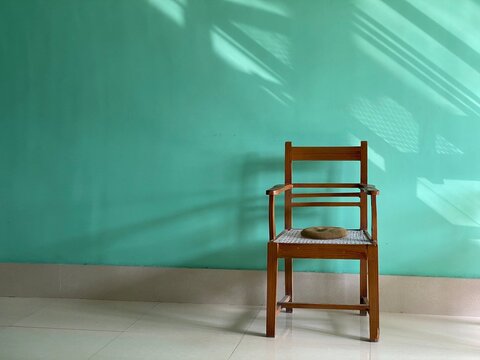 A wooden chair in front of a sun lit background