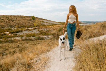 Young woman walking her dog smiling outdoor in sunlight