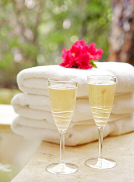 Champagne with folded towels at spa with tropical flower