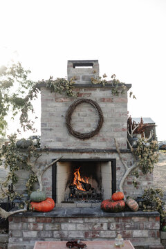 fire crackles in outdoor fireplace decorated with pumpkins