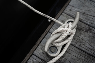 Fototapeta na wymiar Boat Mooring Rope Secured To Cleat On Wooden Dock