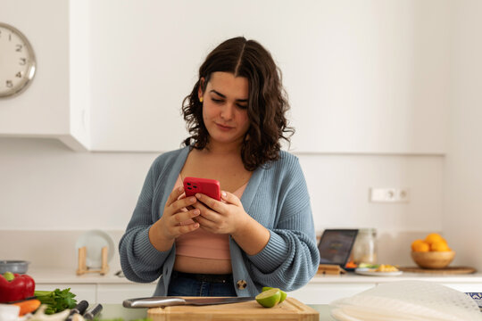 Woman using phone whle cooking