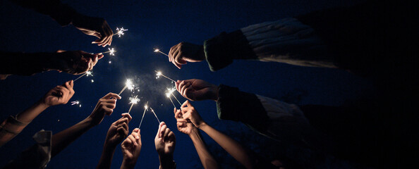 Group of young friends enjoy with burning sparkler in hands together
