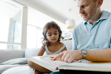 Father reads a book to his daughter