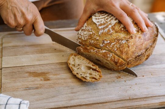 Woman cutting loaf of bread with a large knife