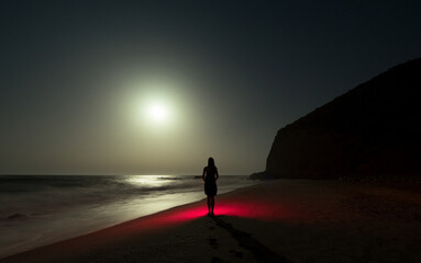 Female silhouette standing on surreal beach at night