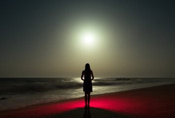 Surreal night woman silhouette standing on the shore