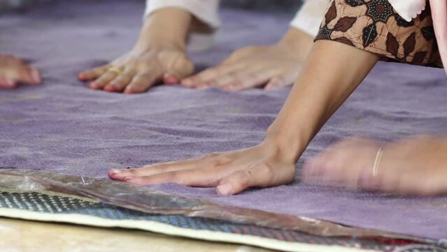 home industry. close-up videos of adult Indonesian women's hands spreading and gluing leaves on cloth to make ecoprint batik.