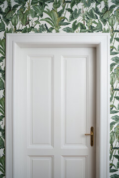 White door surounded by a greenish wallpaper