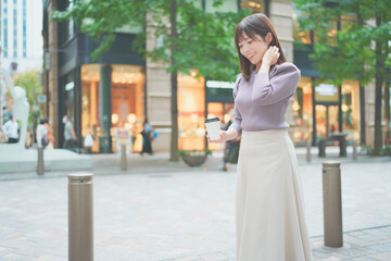 コーヒーカップを持って街を歩く女性