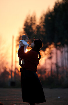 Interaction of asian woman and little baby at sunset