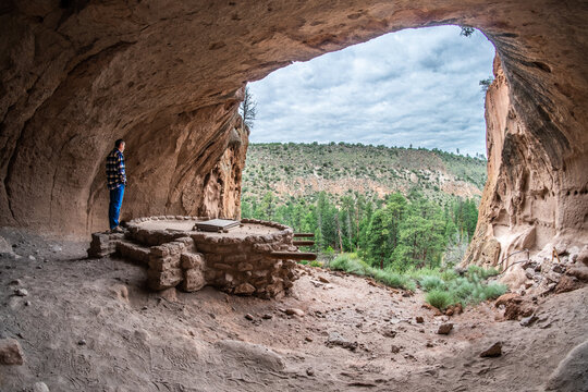 Mature Caucasian man looking watching a kiva built, reconstructed in a rock dwelling area, Alcove House, Bandelier National Monument, New Mexico