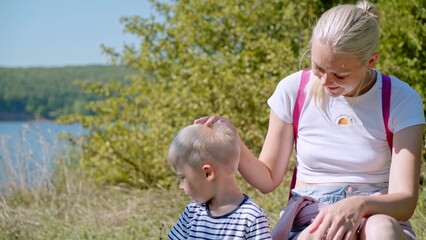 Mom pats her son on the head. She hugs him to her and in every possible way shows him her love and...