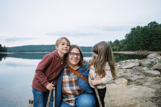 Young smiling mother with her happy children at the lake