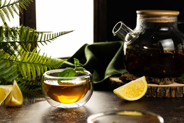 A glass mug with tea in the light is on the table. Custard tea with lemon