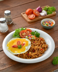 Indomie goreng Indonesian Popular Instant fried Noodle. Served with Sunny Side Egg, Tomato, Cucumber, letucce, and chilli.