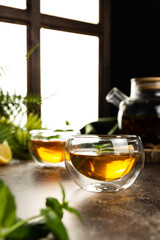 A glass mug with tea in the light is on the table. Custard tea with lemon