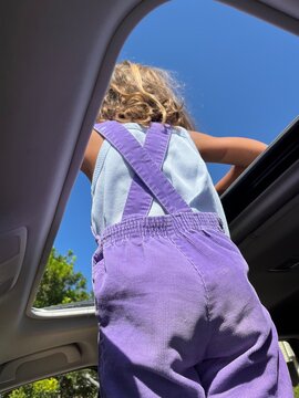 Girl looking out car sunroof