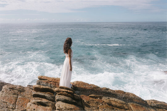 Aerial drone view of bride in an amazing dress standing on a cliff and