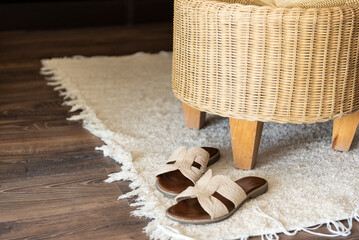 Cozy bedroom with comfortable sandals, wicker chair and white carpet