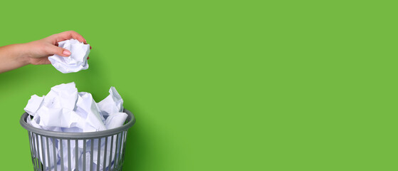 Woman throwing crumpled paper into trash bin on green background with space for text