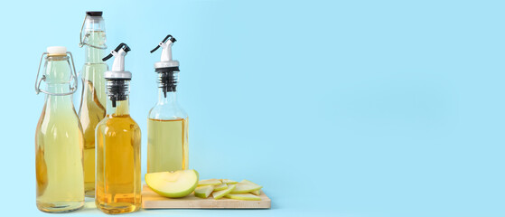 Bottles of apple cider vinegar on light blue background with space for text