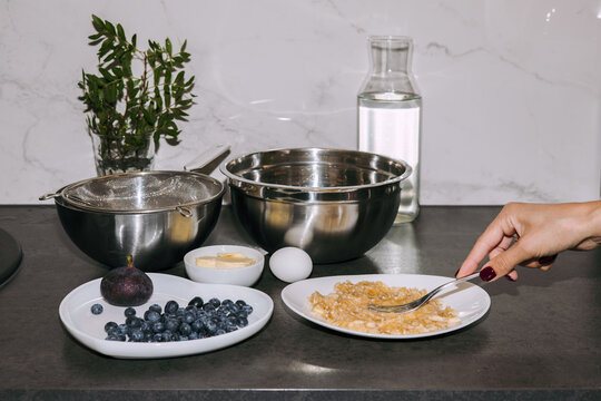 A woman's hand forks a banana in a white plate.  