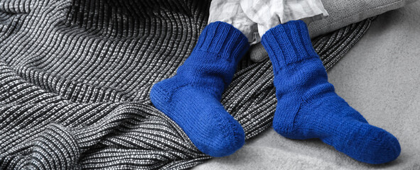 Woman in warm knitted socks resting on bed. Concept of heating season