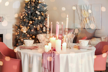 Christmas table setting with burning candles in room