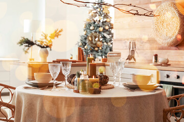 Christmas table setting with burning candles in kitchen