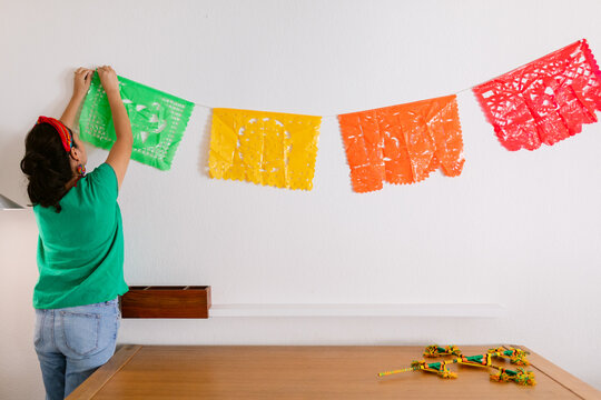 Woman hanging "papel picado" for altar