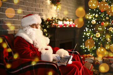 Santa Claus with laptop at home on Christmas eve