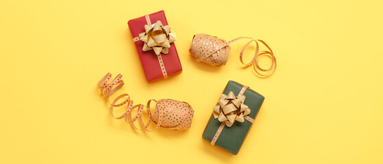 Fototapeta na wymiar Christmas gifts and ribbons on yellow background, top view