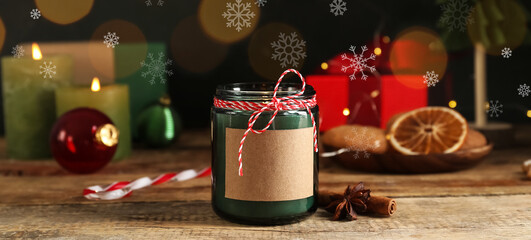 Jar with burning candle and Christmas decor on wooden table
