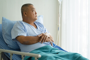 mature cancer patient sitting on the bed in hospital worry before surgery treatment.