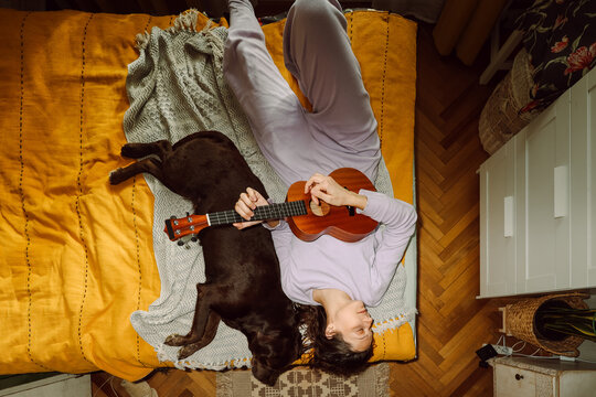 Young woman playing ukulele guitar for her dog