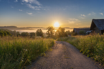 Early morning with rising golden sun in the village. Summer. Ural, Russia.