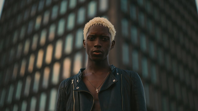 Stylish Dark Skinned Guy On Evening City Street. Behind Him Is High Ri