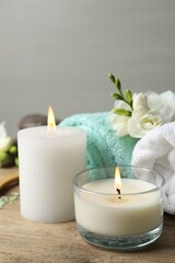 Beautiful composition with burning candles and different spa products on wooden table