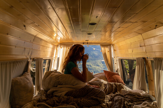 woman drinking cofffe in camper van in the morning