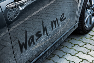 Phrase Wash Me written on dirty car, closeup