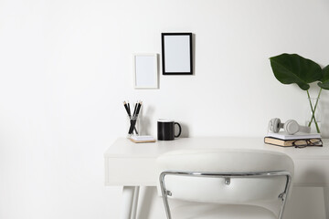 Fototapeta na wymiar Comfortable workplace with white desk near wall at home
