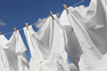 Clean clothes hanging on washing line against sky, closeup. Drying laundry