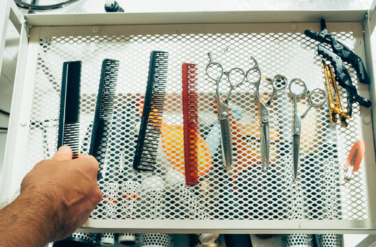 Cropped Image of Hairdresser's Hand Choosing Comb