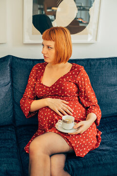 Beautiful Pregnant Red Haired Woman Sitting on Sofa