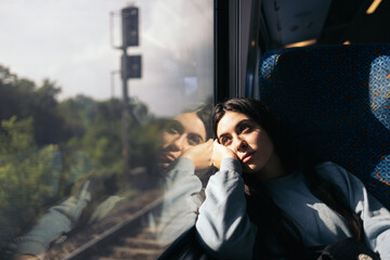 Young woman traveling by train looking out the window