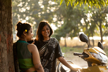 Two Indian woman wearing Sari dress interacting in a park